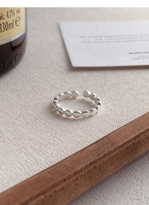Détail d'une bague ouverte perlée en argent S925 sur une surface en tissu texturé élégante