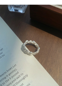 Detail of matte silver rose relief ring placed on vintage book pages with soft lighting