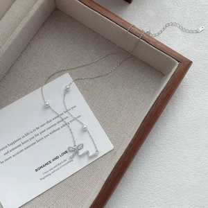 Elegant 925 sterling silver bow necklace with sparkling crystals and white pearls
