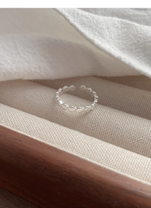Détail macro d'une bague perlée en argent sterling S925 sur un présentoir minimaliste