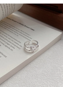 Dettaglio di un anello a doppio strato in argento S925 con zirconi su un libro