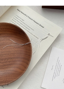 Detailed view of silver S925 tassel earrings on a wooden tray with an artistic card