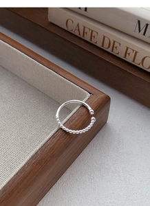 Detailed close-up of a S925 sterling silver beaded ring on a wooden storage box edge