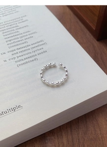 Détails d'une bague perlée en argent sterling S925 posée sur un livre au style minimaliste