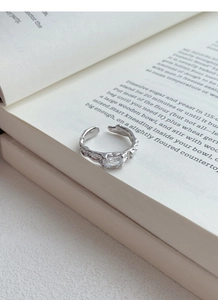 Macro di anello in argento S925 con texture irregolare e zircone su pagine di libro