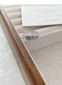 Dettaglio macro dell'anello in argento S925 con tre pietre blu e fascia testurizzata