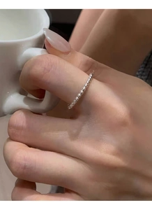 Detail of a minimalist S925 sterling silver beaded ring on hand holding a ceramic cup