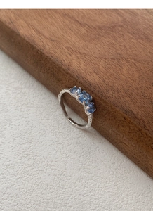 Dettaglio dell'anello aperto in argento martellato con tre brillanti zirconi blu
