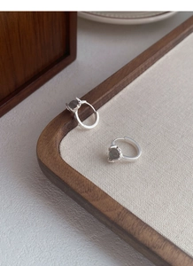 Macro detail of S925 sterling silver hoop earrings with moonstone on a wooden tray