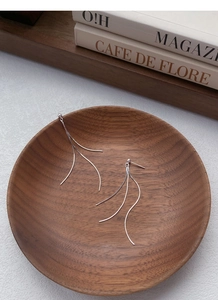 Close-up of minimalist S925 sterling silver long tassel chain earrings on a wood tray