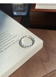 Détail d'une bague ouverte en argent massif S925 à billes posée sur un livre blanc élégant