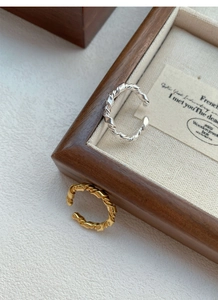 Close-up of knotted S925 sterling silver rings in gold and silver twist design