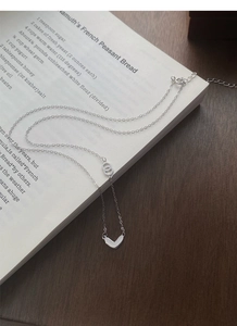 Detail of S999 silver heart necklace with double loops on a vintage book background