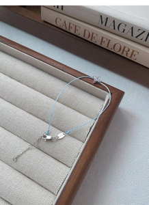 Detail view of S925 sterling silver lobster clasp and clover charm on blue cord bracelet
