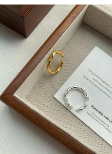 Detail of twisted S925 sterling silver rings in gold and silver finish on display