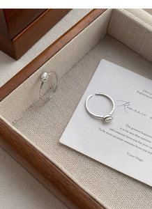 Detail of adjustable S925 silver ring with a white freshwater pearl on a wooden tray