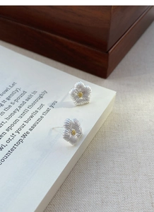 Makro-Detail von S925 Silber Blumenohrringen mit texturierten Blättern auf einem Buch