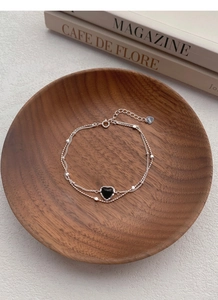 Macro detail of S925 silver double-layer bracelet with black heart charm and beads