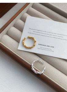 Detailed shot of S925 sterling silver knotted rings in gold and silver on velvet