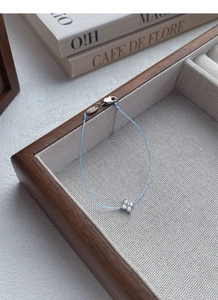 Detail view of S925 sterling silver four-leaf clover charm on a blue woven bracelet
