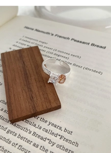 Dettaglio anello in argento S925 con texture a righe e zircone su sfondo di libro