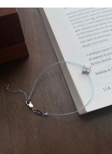 Detail of silver lobster clasp and S925 engraved tag on a blue clover charm bracelet