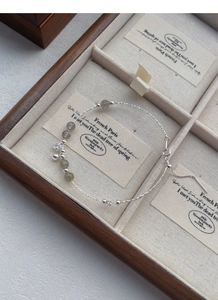 Macro detail of S925 silver beaded bracelet with moonstone and star charms in a wood box