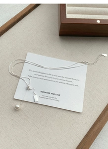 Close-up of S925 silver Y-shaped pearl necklace with polished metal tag and fine chain