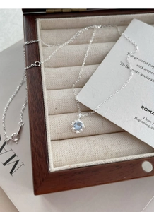 Gros plan du collier fleur en argent S925 avec pendentif en zircon bleu sur boîte