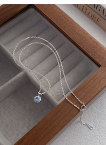Détail du poinçon en argent S925 et du pendentif fleur en zircon bleu sur boîte velours
