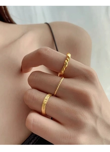 Close-up of three gold-plated silver rings with twisted and hammered textures on hand