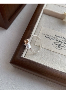 Dettaglio macro dell'anello in argento S925 con ambra e zircone quadrato su legno