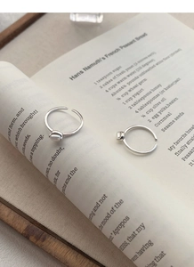 Elegant silver pearl rings displayed on an open vintage book page in warm lighting