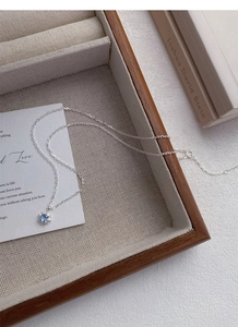 Gros plan du collier en argent S925 avec pendentif fleur en zircon bleu sur plateau