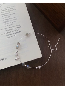 Macro detail of S925 silver bracelet with labradorite beads and floral charm pendant