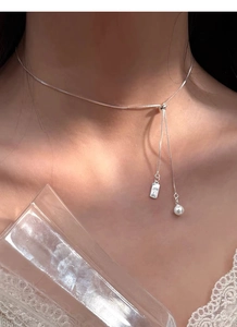 Detailed shot of an adjustable silver pearl necklace with a pendant worn by a model