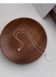 Gros plan du collier fleur en argent S925 avec zircon bleu sur plateau en bois sombre