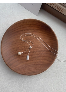 Detail of S925 silver Y-necklace with creamy pearl and polished rectangular pendant