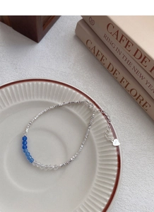 Detail of S925 sterling silver beaded bracelet with blue crystal accents on ceramic plate