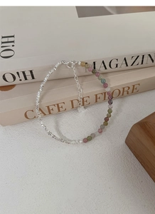 Detailed shot of S925 silver beads and multi-color tourmaline bracelet on books