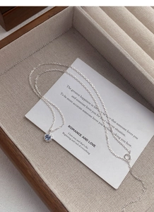 Gros plan du collier en argent S925 avec pendentif en zircon bleu sur plateau en lin