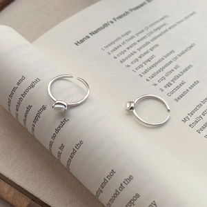 Minimalist S925 sterling silver open ring with natural white rice pearls on a book