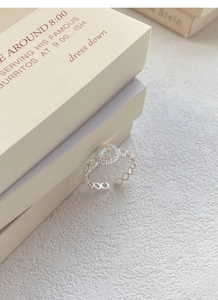 Dettaglio dell'anello in argento con pietra di luna e fascia a catena su sabbia