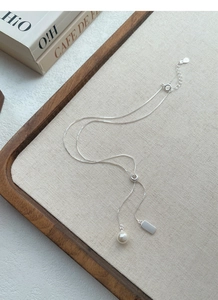 Detail of S925 silver Y-shaped necklace with white pearl and sleek rectangular tag