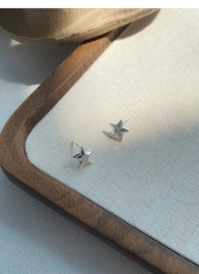 Gros plan détaillé des boucles d'oreilles étoile en argent S999 avec zircon central