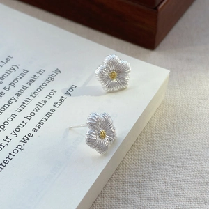 Elegante S925 Sterlingsilber Blumenohrstecker mit goldener Mitte auf Vintage-Buchseiten