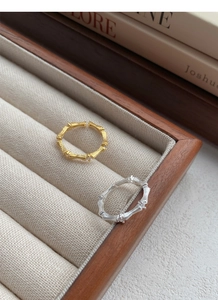 Close-up of gold and silver bamboo rings with zircon accents on a velvet display box