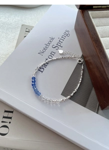 Macro shot of S925 sterling silver bracelet with blue crystal beads on white books