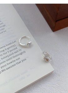 Close-up of S925 sterling silver hoop earrings with iridescent moonstone on a book page