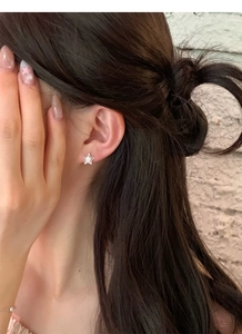 Gros plan d'un clou d'oreille étoile en argent S999 avec cristal sur l'oreille du modèle